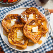 Four slices of buttermilk french toast with butter and maple syrup.