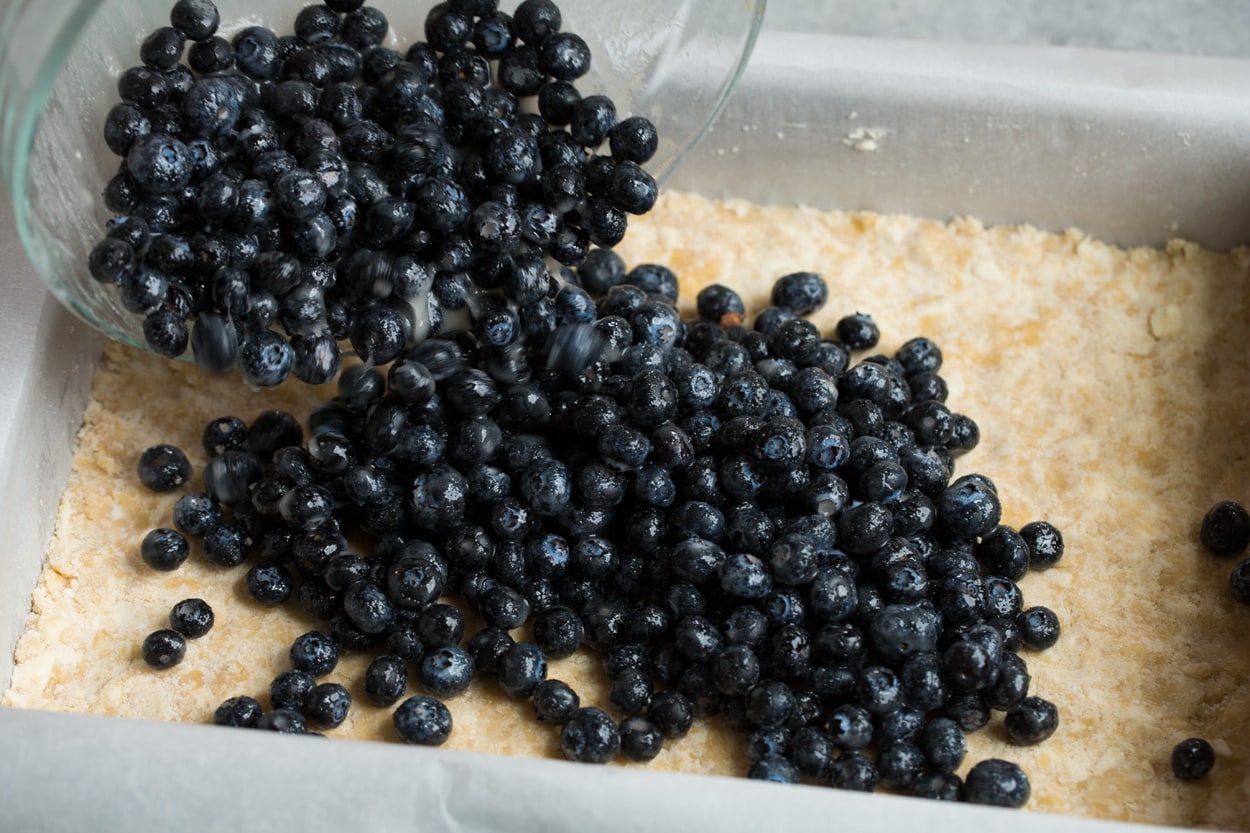 adding fresh blueberry filling to crumb bars base