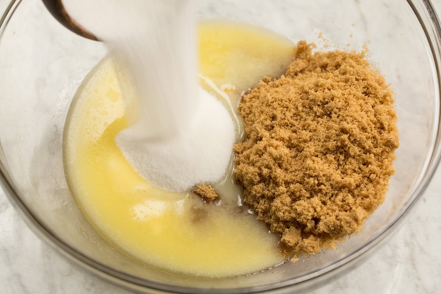 Skillet Chocolate Chip Cookie White sugar and brown sugar added to melted butter in glass mixing bowl.