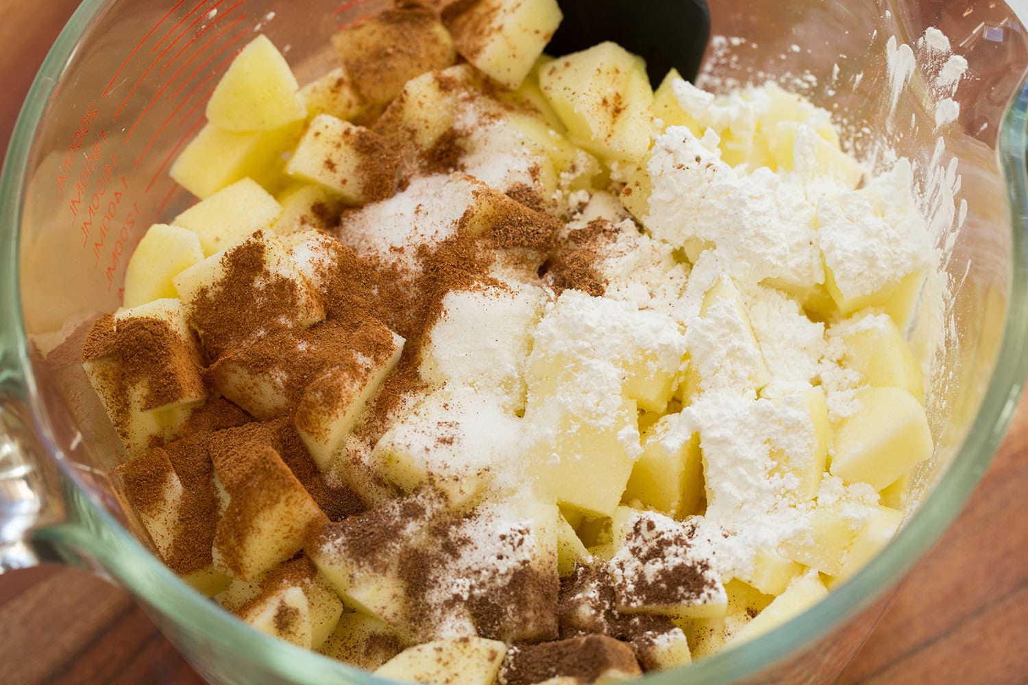Apple Pie Bars Apples, cinnamon, sugar and cornstarch in a glass bowl.