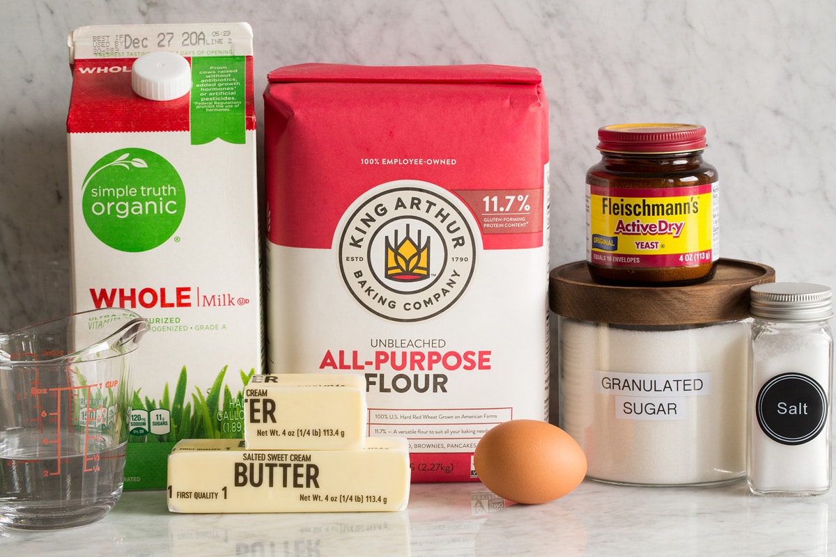 Best Dinner Rolls Image of ingredients used to make bread. Includes flour, yeast, butter, egg, milk, salt, sugar and water.