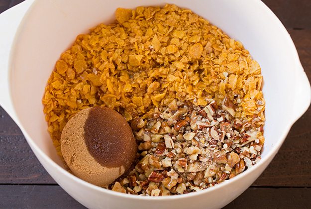 Note that if you are making this in advance to refrigerate then bake the following day, don't add the corn flake topping until baking or it will become stale. Also I'd recommend placing cold casserole in cool oven and let it preheat with oven. Making cornflake pecan topping for sweet potato casserole.