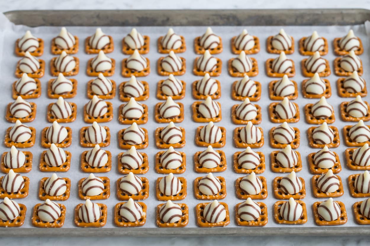 Pretzel M&M Hugs Adding hugs to pretzels on baking sheet.