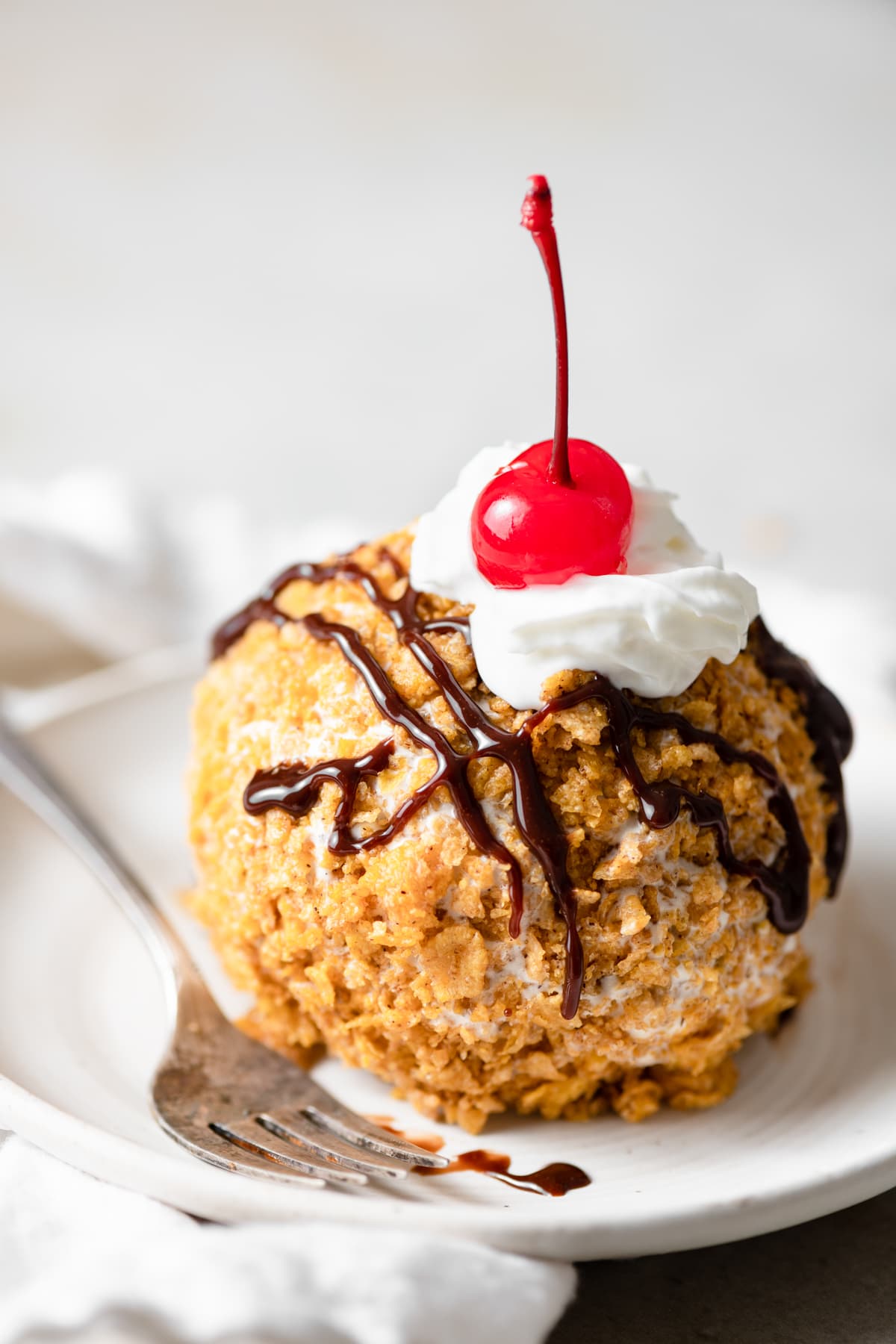 BEST EVER Easy Fried Ice Cream! Close up image of fried ice cream on a dessert plate with fork on the left side.