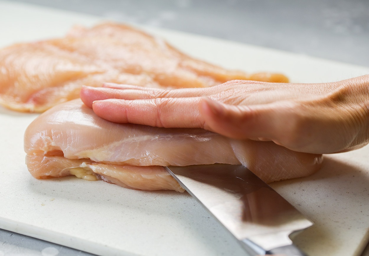 BEST Chicken Parmesan recipe! Showing how to make chicken parmesan. Starting by butterflying chicken breasts on a cutting board.