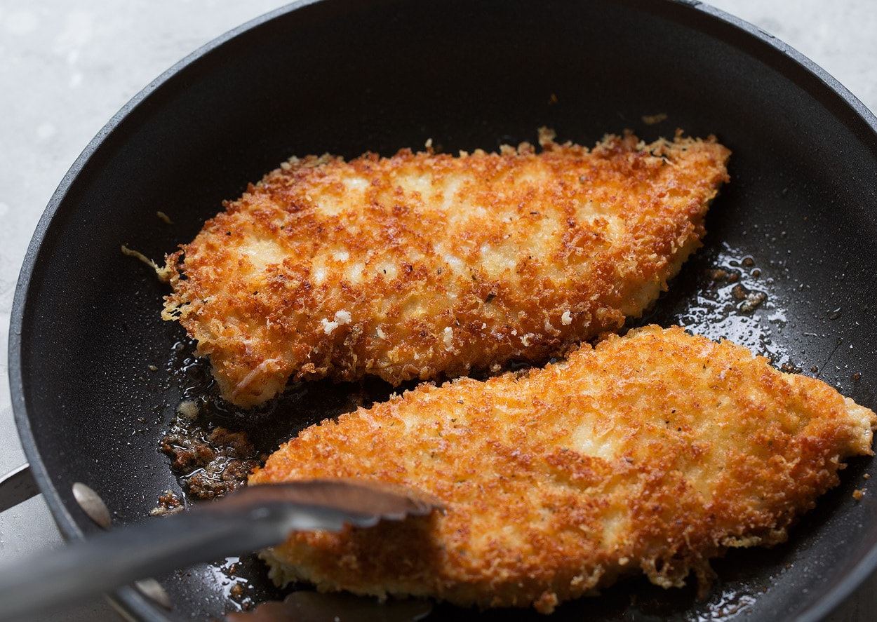 BEST Chicken Parmesan recipe! Searing chicken parmesan pieces in olive oil in black non-stick skillet until golden brown.