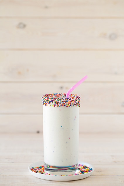 birthday cake milkshake in glass rimmed with sprinkles