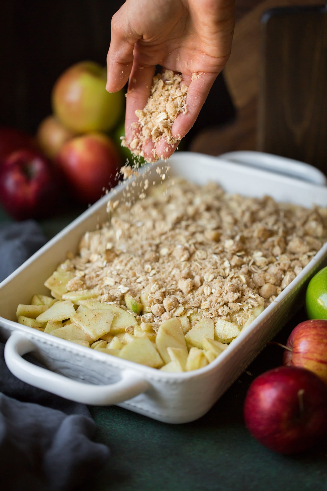 Apple Crisp Recipe sprinkling apple crisp topping onto sliced apples