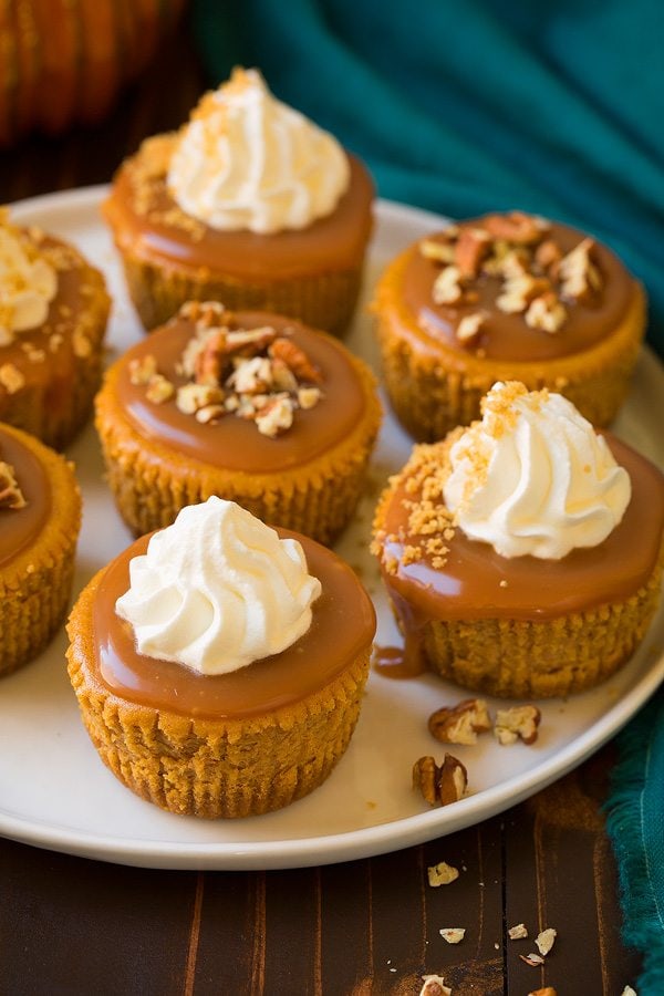 Mini Pumpkin Cheesecakes Mini Pumpkin Cheesecakes with Salted Caramel Sauce on a white serving plate.