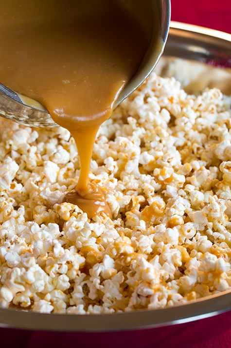 Caramel Popcorn. Pouring caramel coating over plain popcorn in a large mixing bowl.