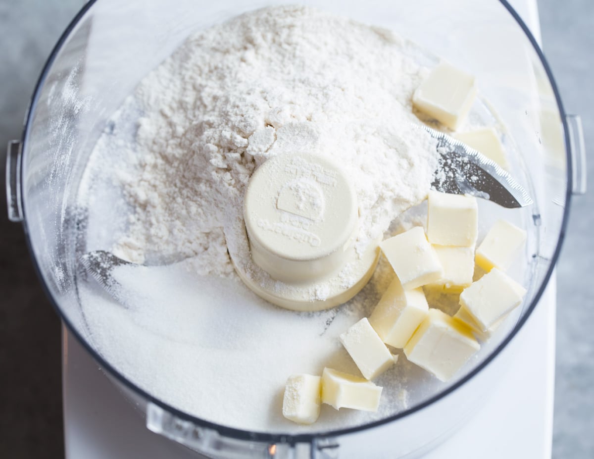 Showing how to make blueberry muffins, pulsing butter, flour and sugar for topping in food processor.