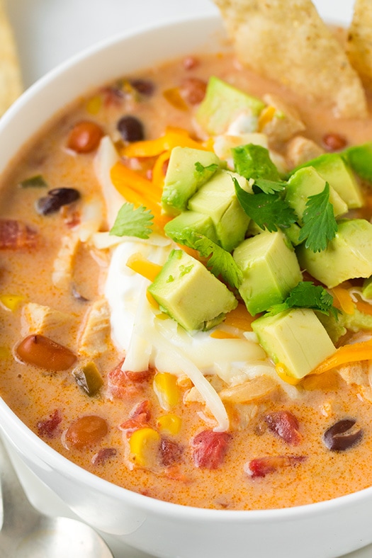 Creamy Chicken Tortilla Soup. A hearty, warming and comforting soup made with juicy chicken, vegetables and loaded with delicious toppings. Best of all this soup is whipped up in under 30 minutes and couldn't be easier! | Chicken Soup | Mexican Soup | #veggiesdontbite #soup #chicken #tortilla A close up of Creamy Chicken Tortilla Soup topped with avocado