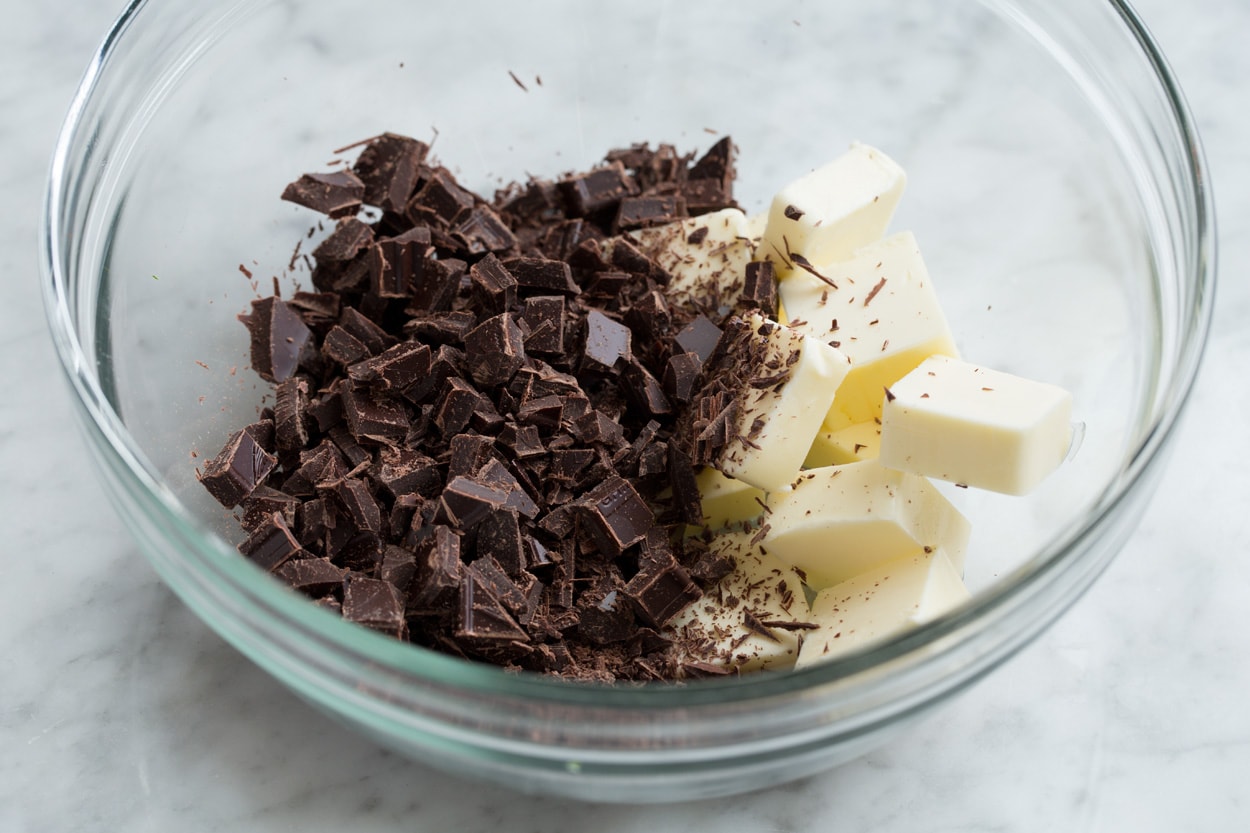 The BEST Flourless Chocolate Cake! Showing how to make flourless chocolate cake, adding chopped chocolate and butter to a glass mixing bowl.
