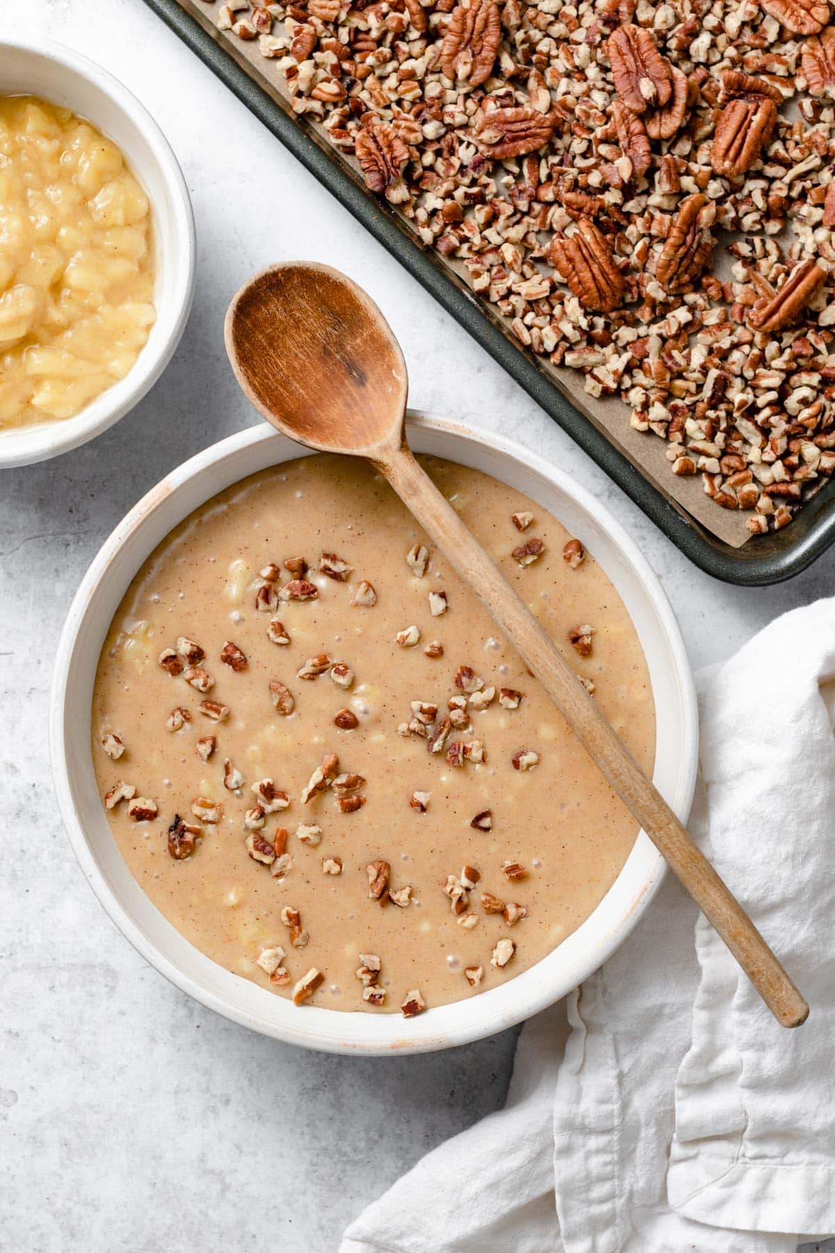Hummingbird Cake Showing how to mix cake batter ingredients in a ceramic mixing bowl using a wooden spoon to fold in pecans.