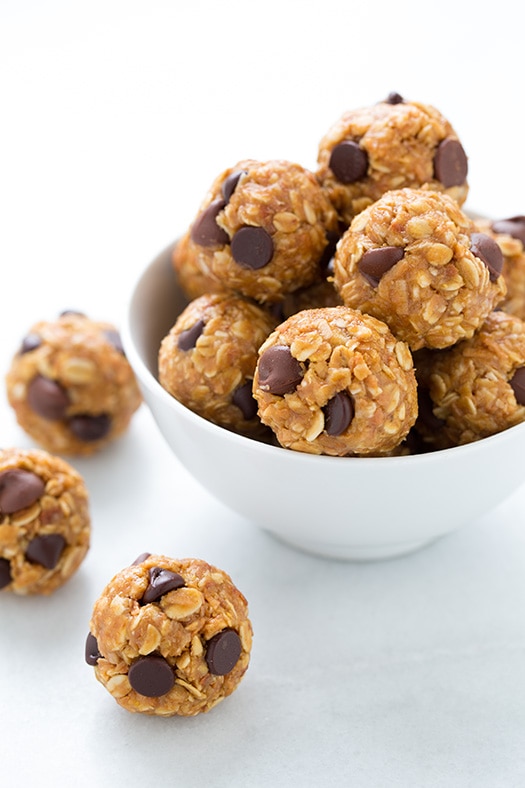 No Bake Energy Bites. The perfect on the go midday snack that couldn't be easier to make at home. | Energy Snacks | Energy Balls | #cookingclassy #bites #energy #snacks A close up of No Bake Energy Bites in a white bowl with a couple scattered beside it