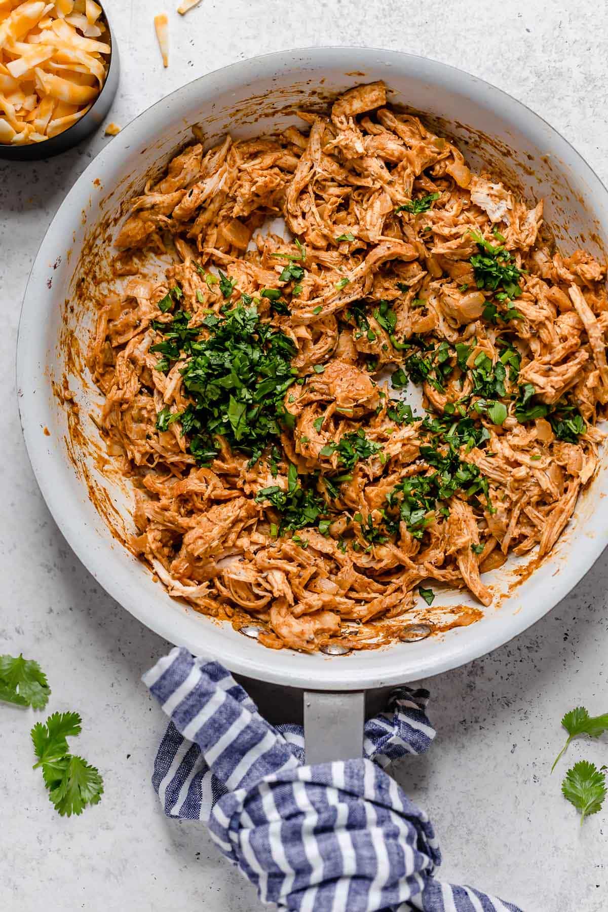 Baked Chicken Taquitos Chicken Taquito filling in a white skillet, garnished with cilantro on top.