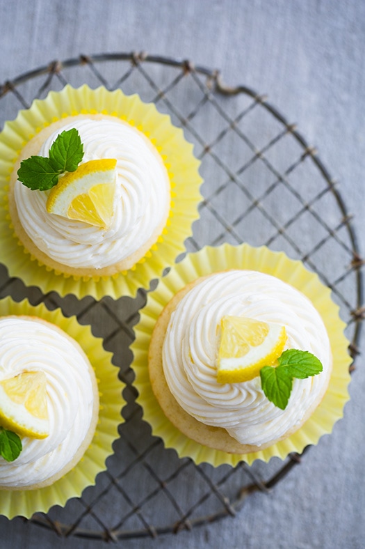 Lemon Cupcakes garnished with mint leaves and lemon wedges