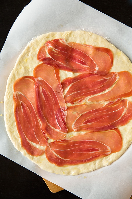 uncooked pizza crust topped with prosciutto
