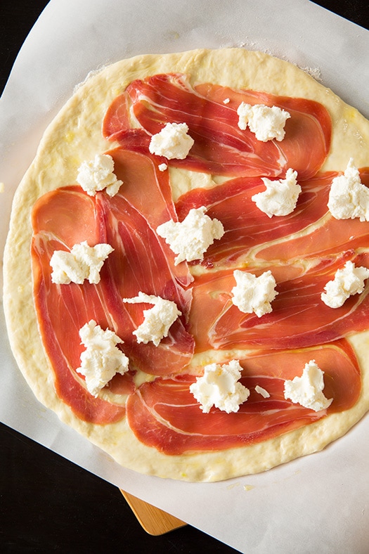 uncooked pizza crust topped with prosciutto and ricotta