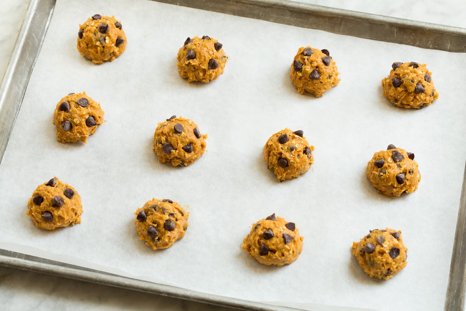 Pumpkin Oatmeal Chocolate Chip Cookies Cookie dough balls on a baking sheet.