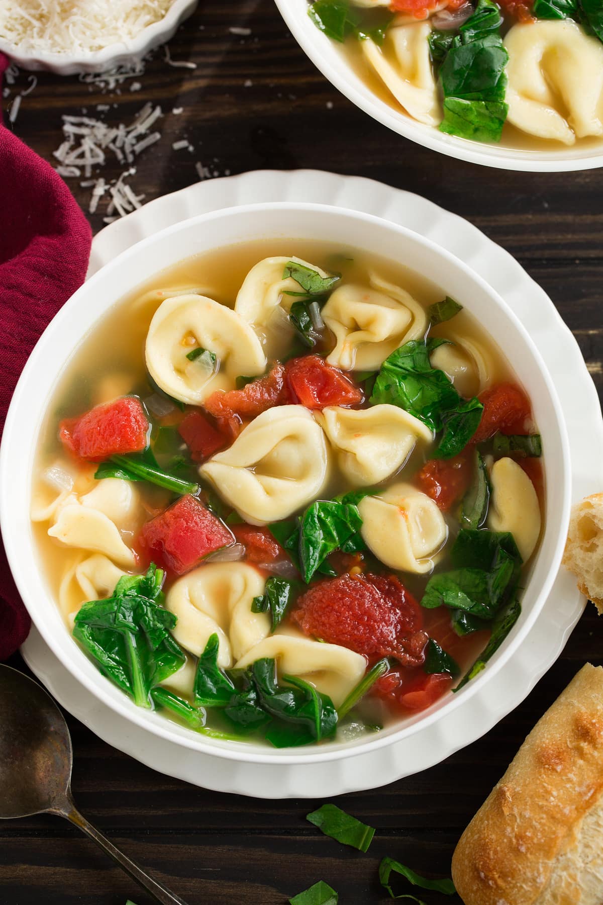 Tortellini Soup with Fresh Spinach Tomato and Garlic Overhead image of tortellini soup in a white serving bowl.