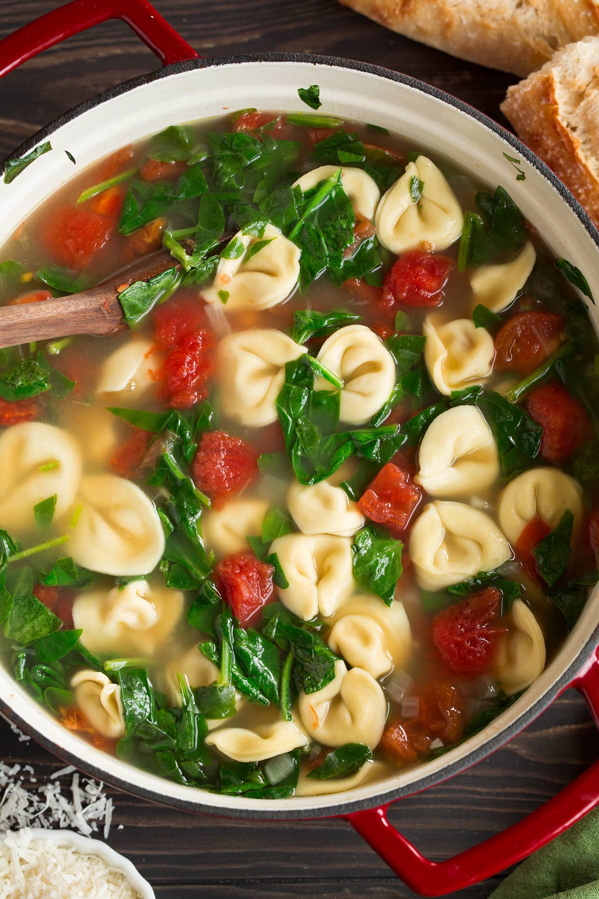 Tortellini Soup with Fresh Spinach Tomato and Garlic Overhead image of tortellini soup in a large red pot.