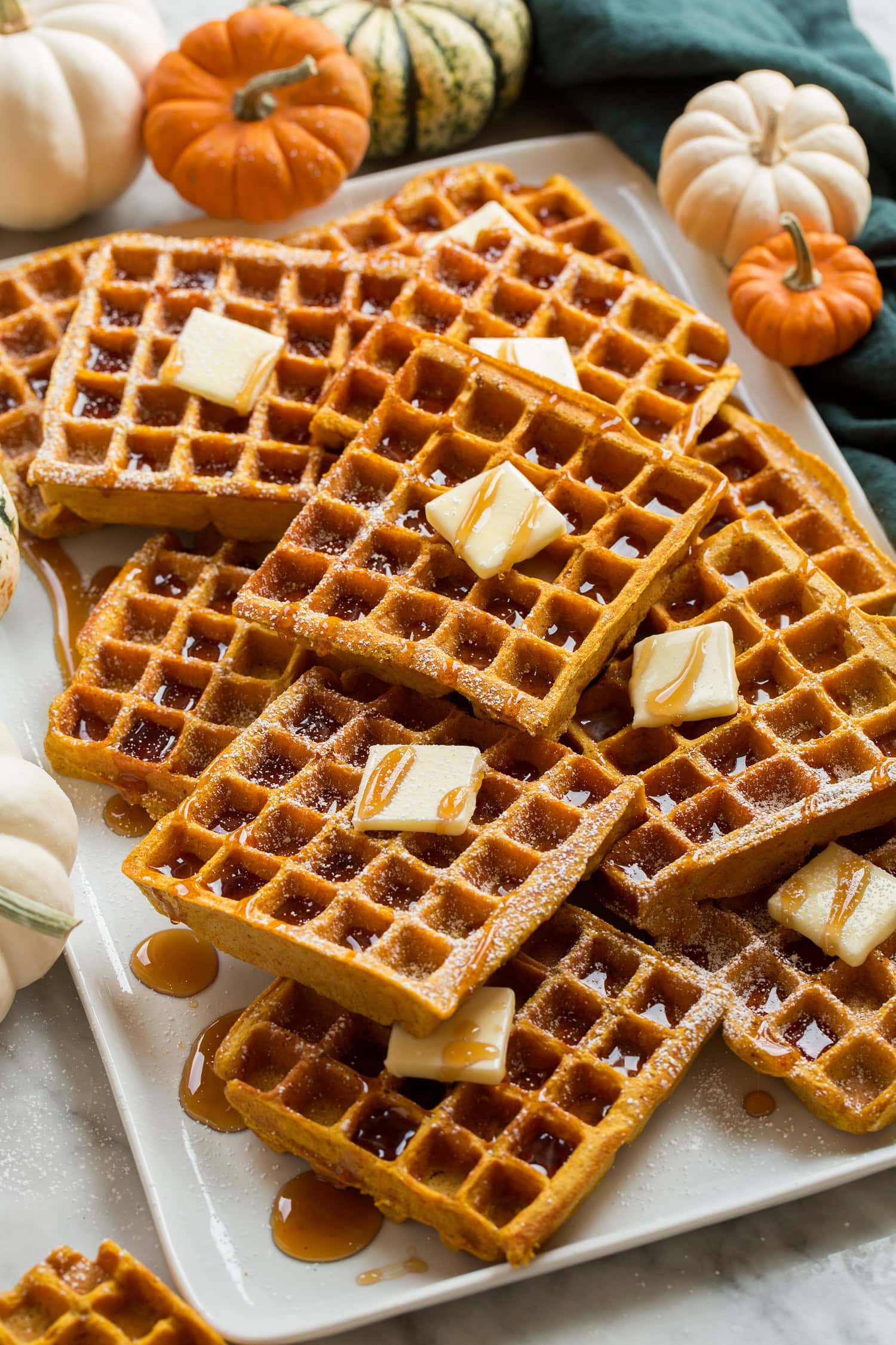 Pumpkin Waffles Stacked homemade pumpkin waffles on a platter shown from a the side.
