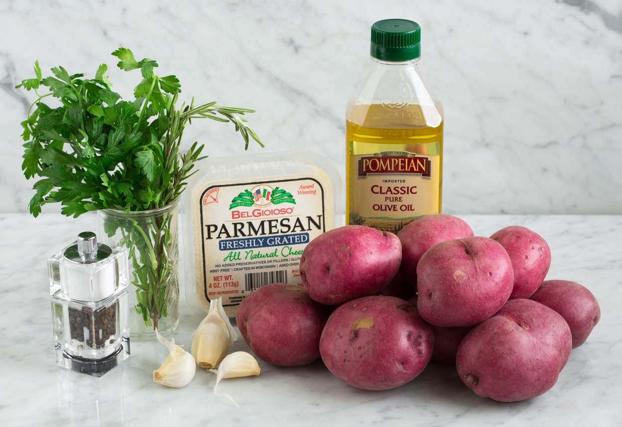 Roasted Potatoes with Garlic Parmesan and Herbs Ingredients needed for herb roasted potatoes shown here including red potatoes, olive oil, parmesan, garlic, herbs, salt and pepper.