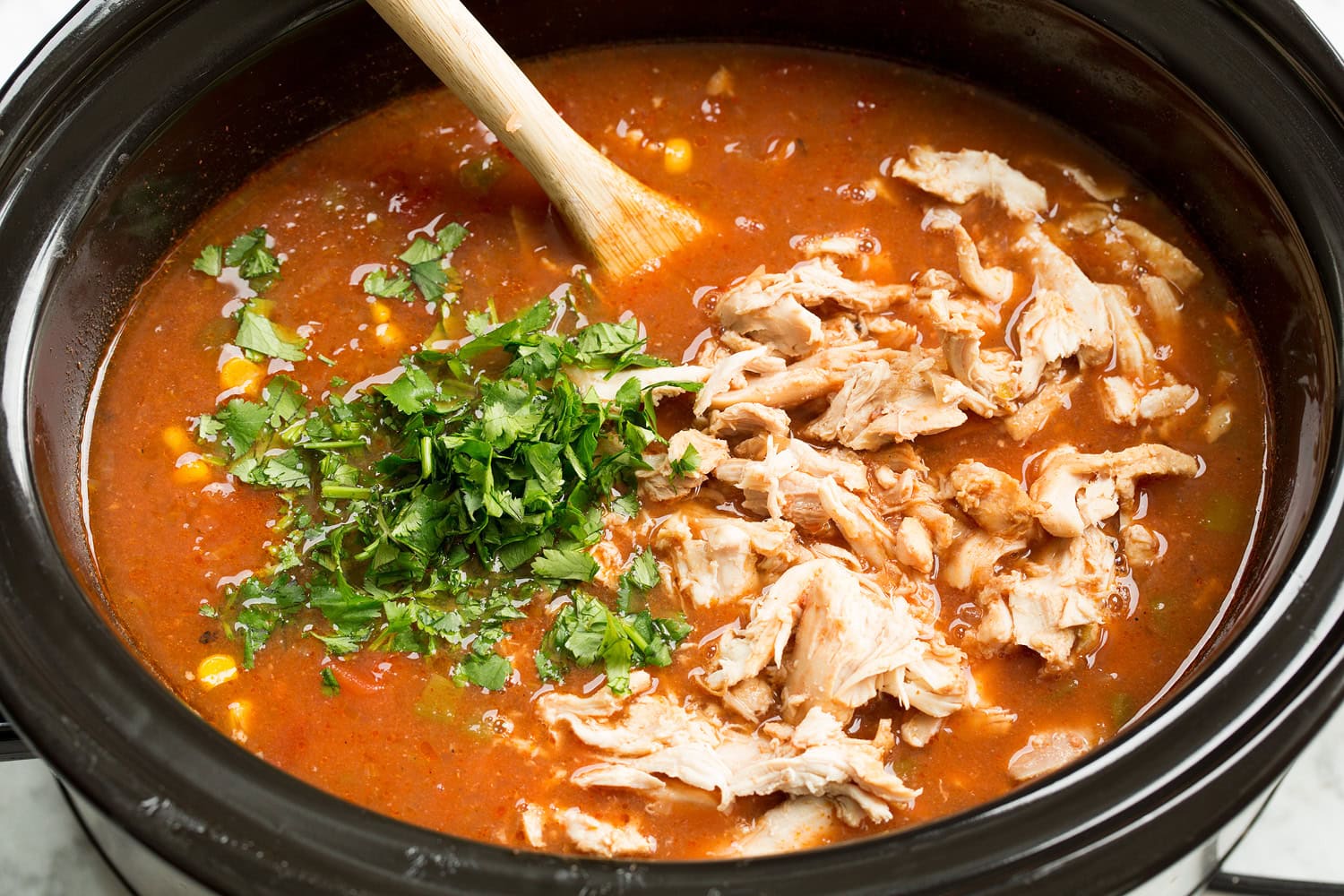 Slow Cooker Chicken Tortilla Soup Cooked shredded chicken added back to slow cooker.