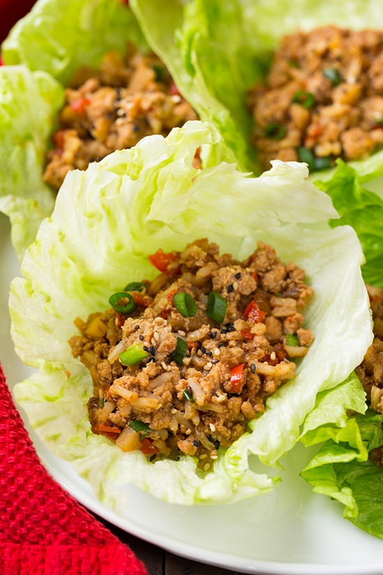 Slow Cooker Asian Chicken Lettuce Wraps. So simple to put together and make such a delicious and healthy weeknight dinner. These wraps are so easy to adapt and can be topped with your favorite sauces, dips and veggies. #cookingclassy #wraps #Asianfood #chicken A close up of Slow Cooker Asian Chicken Lettuce Wraps on a white plate