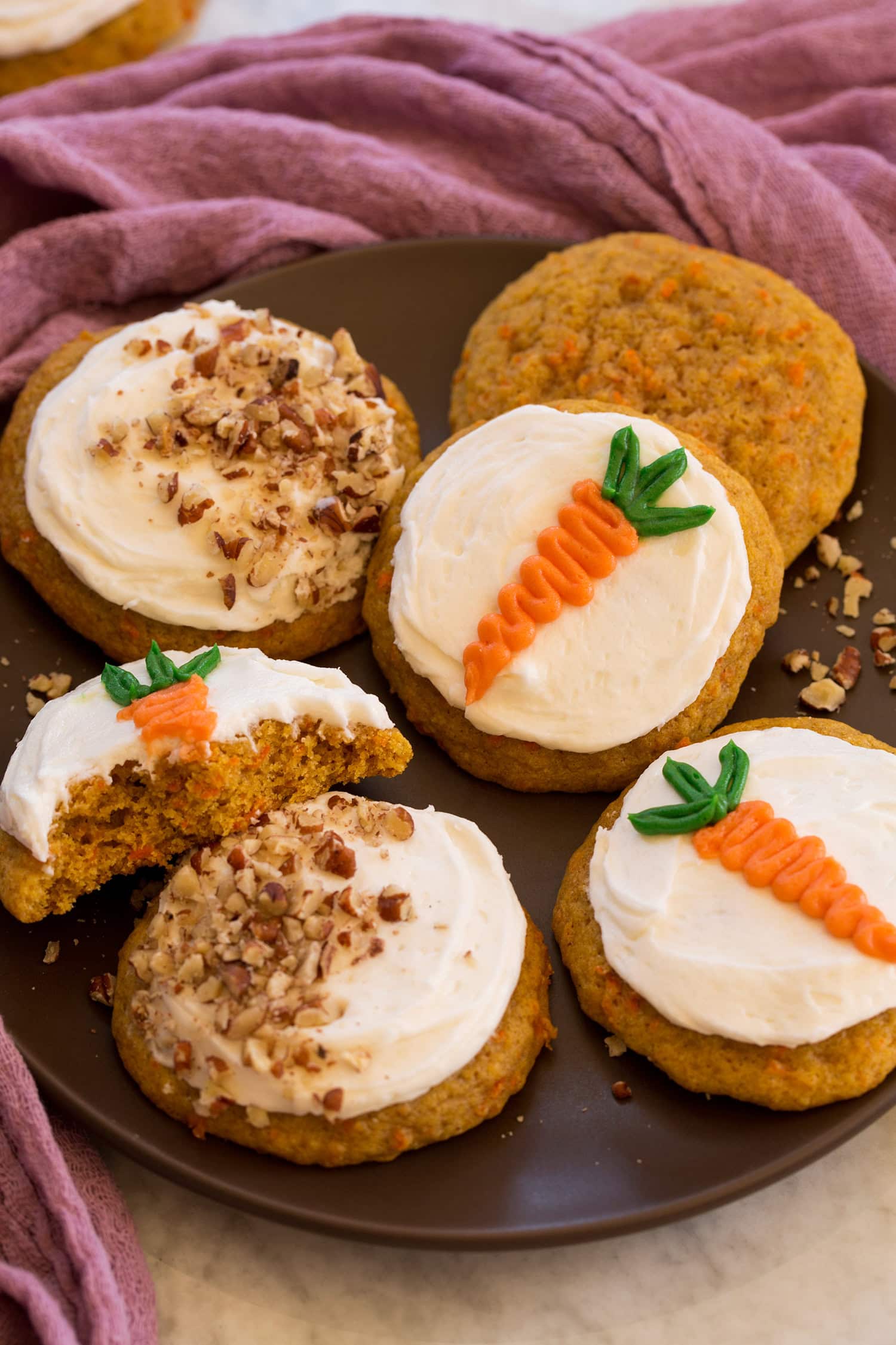 Plate of carrot cake cookies with decorations and pecans on frosting.