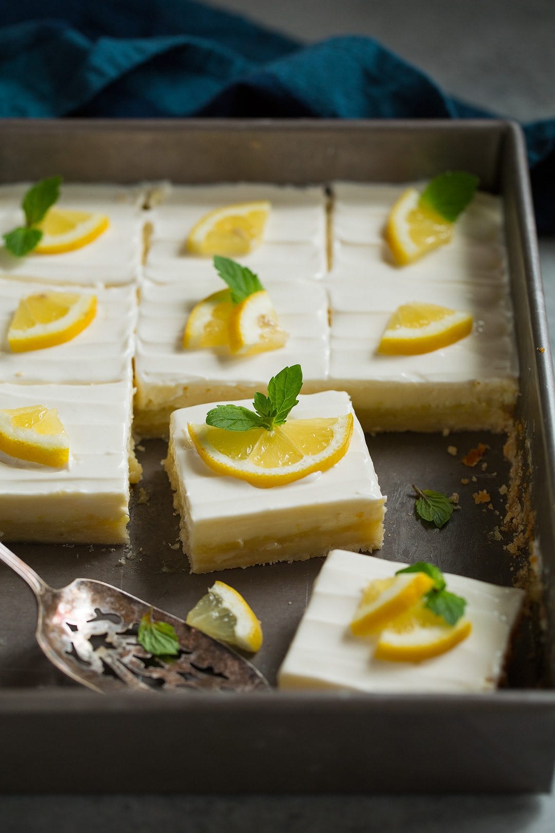 pan of lemon bars garnished simply with lemon wedges and fresh mint