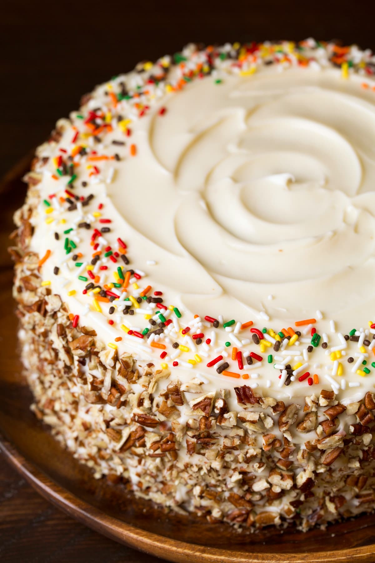 Spice Cake A whole round spice cake without any slices cut. It's covered with a cream cheese frosting, chopped pecans around the edges and fall sprinkles around the top.