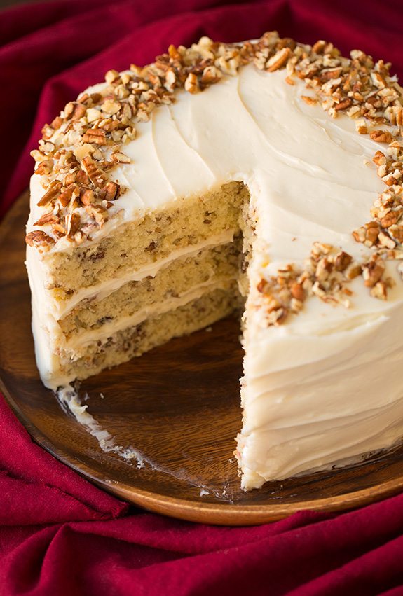 Butter Pecan Cake Butter Pecan Cake on a wooden platter. A large slice is removed from cake to show interior.
