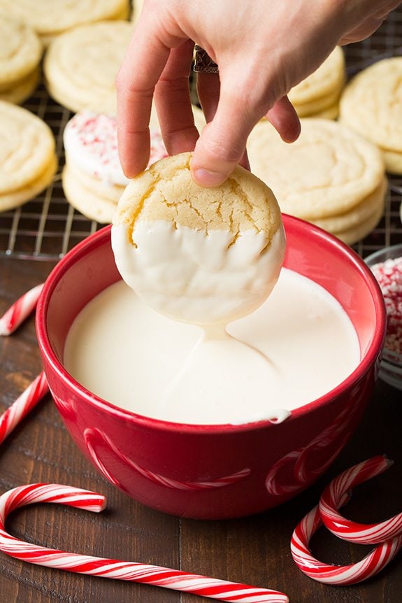 White Chocolate Dipped Peppermint Sugar Cookies Dipping a sugar cookie into a bowl of melted white chocolate.