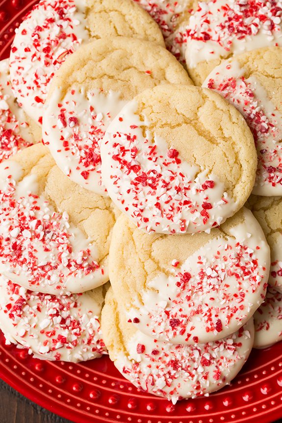 White Chocolate Dipped Peppermint Sugar Cookies Sugar cookies flavored with peppermint, dipped in white chocolate and covered with crushed candy canes. Cookies are shown served on a red plate.