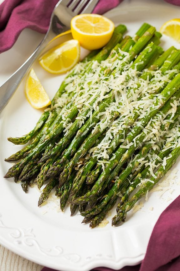 Roasted Parmesan Asparagus on a white platter with lemon wedges