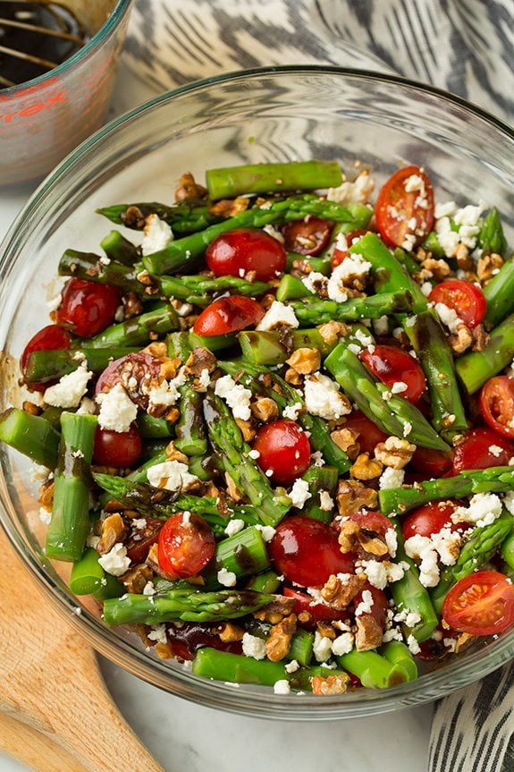 A super delicious asparagus, tomato and feta salad drizzled with an easy balsamic vinaigrette. This salad uses few ingredients but they're all powerful in flavor creating an incredible salad that you won't be able to stop eating! #cookingclassy #asparagus #tomato #feta #salad Asparagus, Tomato and Feta Salad in a glass bowl