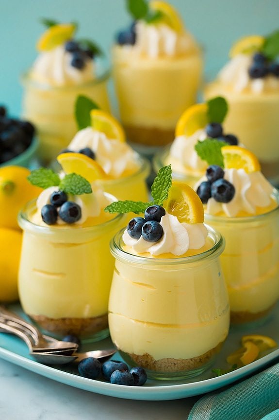 Soft, light and delicious this lemon mousse is the ultimate spring summer dessert. Made with a graham cracker base and a smooth, silky and luscious whipped cheesecake topping it's pretty hard to resist! #cookingclassy #lemon #cheesecake #mousse Lemon mousse in individual glasses topped with whipped cream