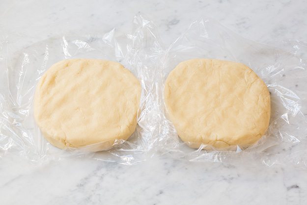two discs of sugar cookie dough on plastic wrap