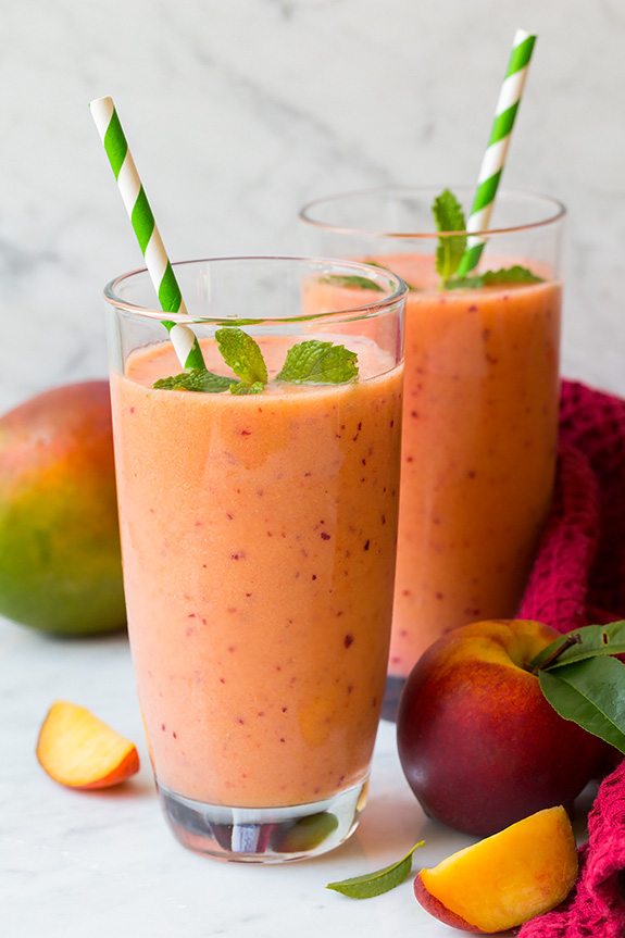 two glasses of mango strawberry peach smoothies with striped straws