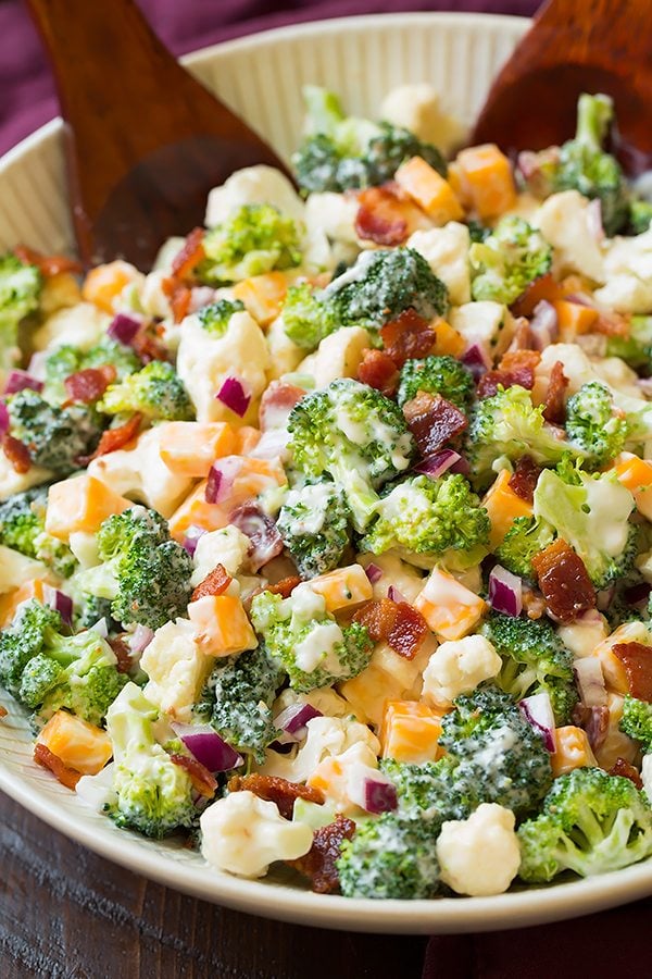 Broccoli and Cauliflower Salad will quickly become a staple recipes! It's always a crowd favorite, who knew people could love broccoli so much? | Broccoli Salad | Salad Side Dish | Salad With Bacon | #cookingclassy #broccoli #salad #bacon #cheese Broccoli and Cauliflower Salad in a bowl with salad servers at the side