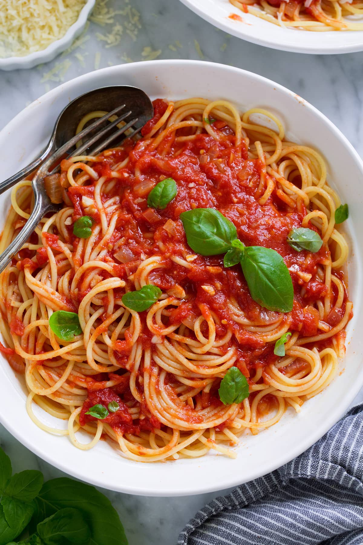Homemade Marinara Sauce - so much better than the bottled stuff! This is authentic, fresh tasting sauce that you'll want to make again and again! Perfect over just about any type of pasta or served with cheese tortellini. It freezes really well too! #marinara #sauce #recipe #italianfood #dinner #lunch Marinara sauce tossed with spaghetti in a pasta bowl.