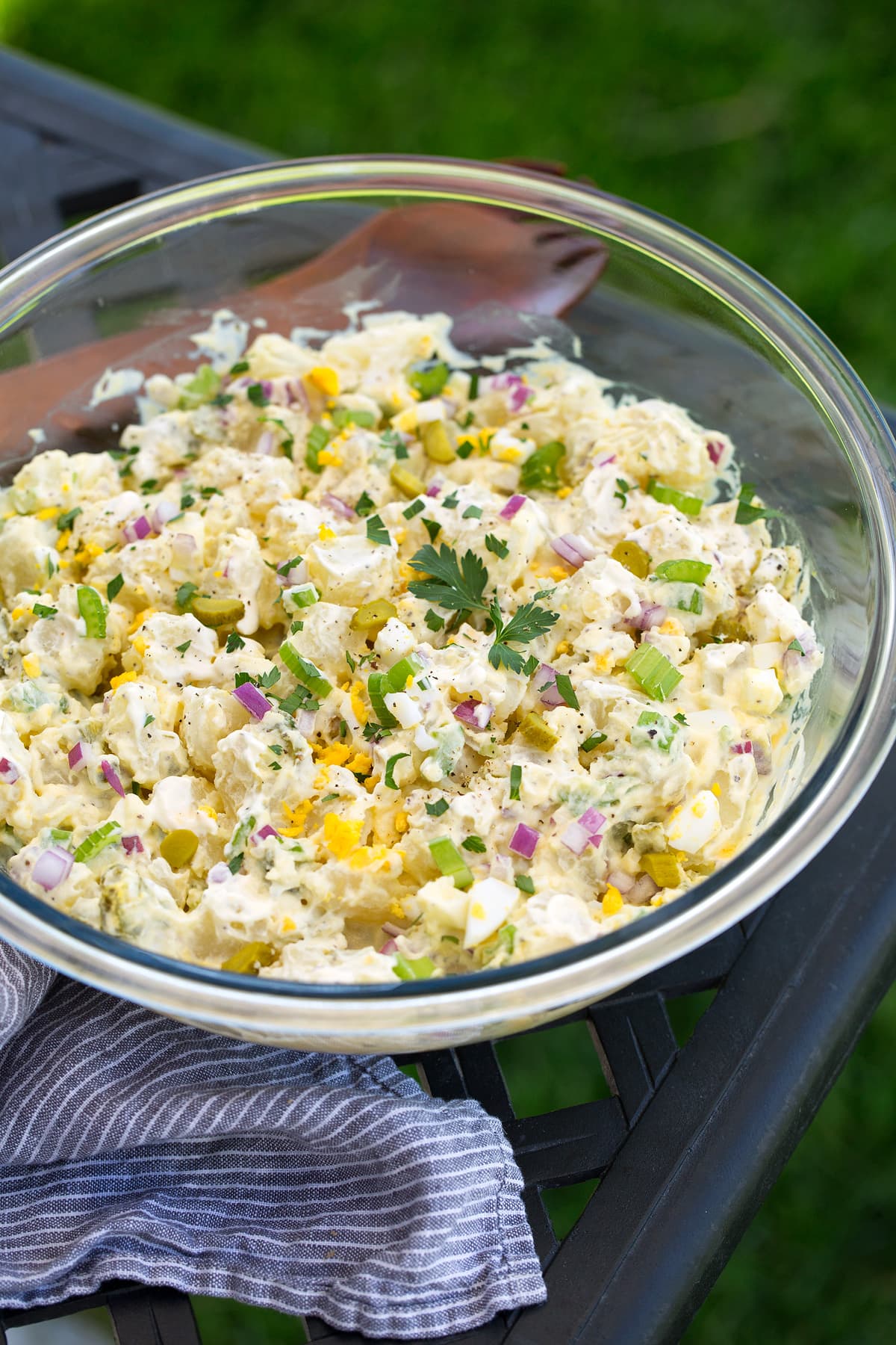 The the BEST potato salad! The texture is rich and creamy, it's perfectly flavorful, it's hearty, and it has all the best textures. | Potato Sides | Salads For Barbecues | #potato #salad #sides #bbq #cookingclassy A glass bowl of potato salad on a table