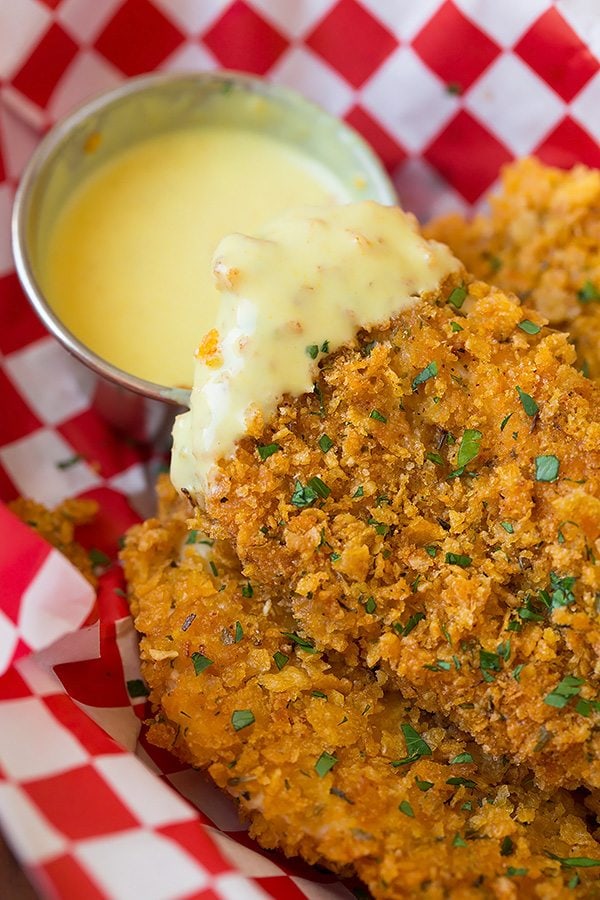 Chicken Strips Recipe Close up image of a chicken strip dipped in honey mustard sauce.