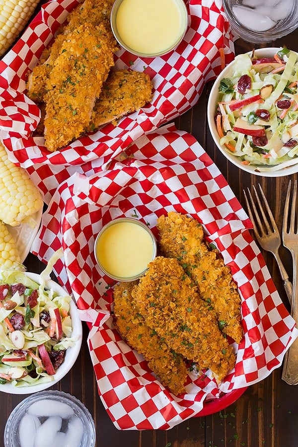 Chicken Strips Two servings of baked chicken strips shown here along with a side of coleslaw and corn on the cob.