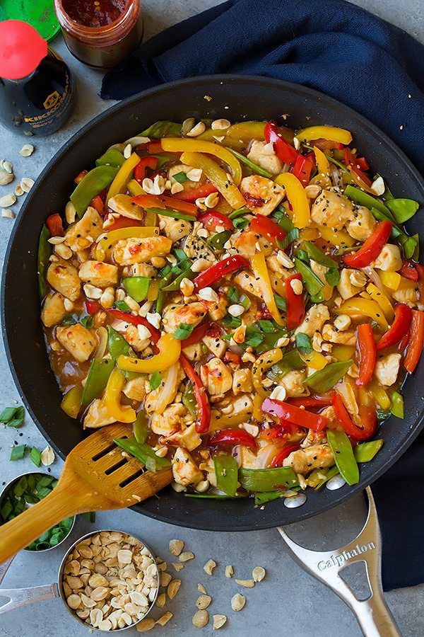 Szechuan Chicken Stir-Fry in metal skillet with wooden spatula 
