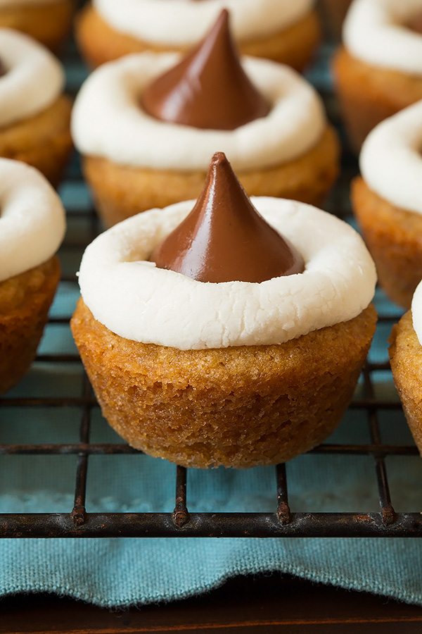 Mini S'mores Cookie Cups Close up image of s'more cookie cup. Graham cracker cookie base with marshmallow halve in middle and a chocolate hershey's kiss on top.