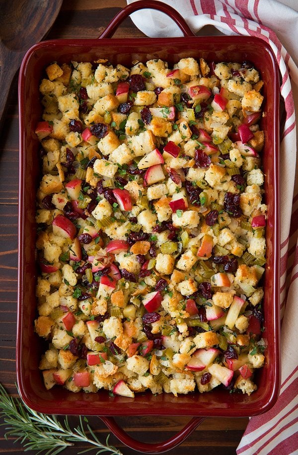 Apple Cranberry Rosemary Stuffing Overhead image of stuffing in a red casserole dish on a dark wooden surface.