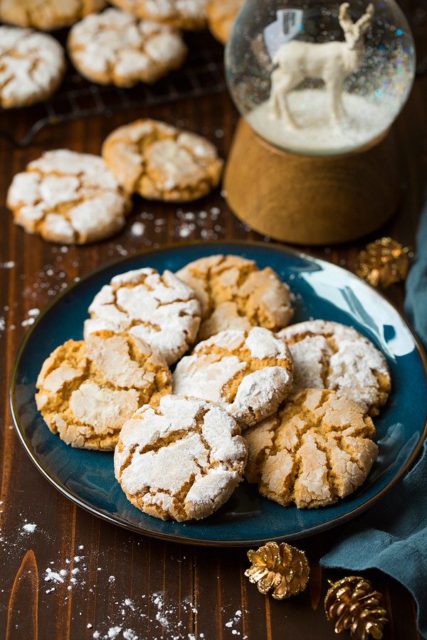 Peanut Butter Crinkles Seven Peanut Butter Crinkle Cookies on a blue plate set over a dark wooden surface. There is a snow globe in the background.